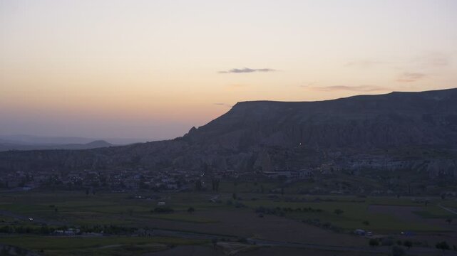 Cavusin village sits nestled in Cappadocia landscape at dusk with illuminated homes in Turkey