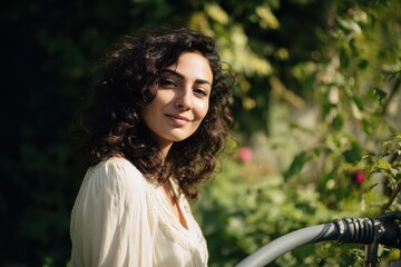 A radiant young woman with beautiful dark curly hair smiles serenely embracing the natural beauty of her garden