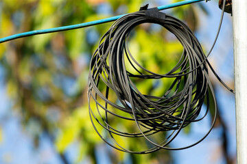 Close up of black wire on electric pole with green nature background.