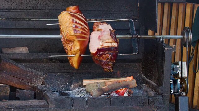 Traditional Pork Knuckle Rotisserie Over Wood Fire at Outdoor Market