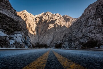 Scenic highway cutting through rugged mountains, vibrant sunset illuminating the path ahead, capturing the essence of ambition and exploration in nature's grandeur