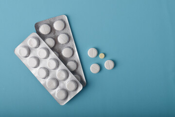 Tablets in a blister packaging isolated on blue background, healthcare and medicine concept