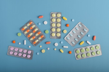Various medicine capsules, pills and tablets in blister packs isolated on blue background, health...