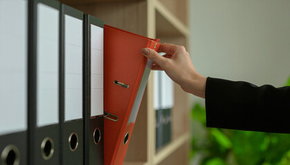A woman is working in an office and takes a folder out of a cabinet.