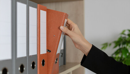 A woman is working in an office and takes a folder out of a cabinet.