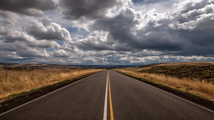 Expansive rural landscape with a straight two lane paved road marked by yellow double lines,