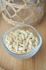 Pine nuts in a glass bowl on a wooden table
