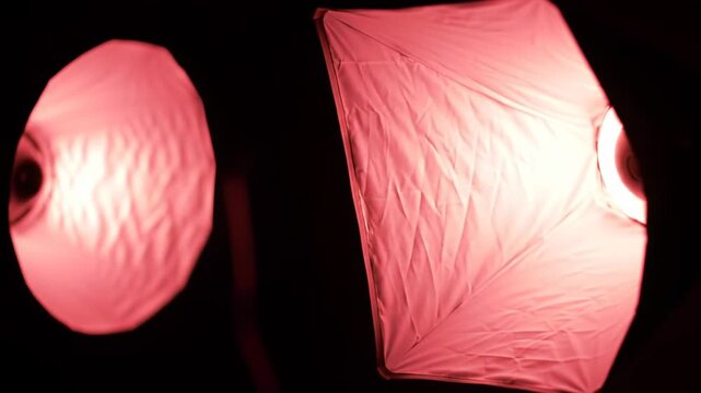 Studio lighting setup with softbox and umbrella flashes in dark room, photography equipment, light sources