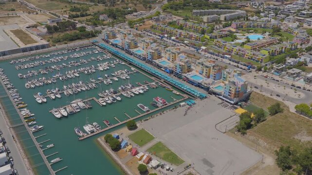 Drone flyover moored boats towards to colorful luxury villas by Albufeira Marina, Algarve