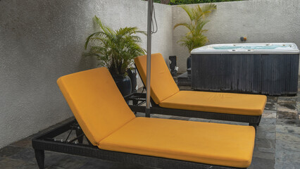 The relaxation area at the spa. Lounge chairs with soft mattresses against the wall. The Jacuzzi is nearby. Palm trees in pots. Tiled floor. Resort