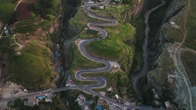 High-angle drone shot showing winding mountain road and steep green valleys near Erbil