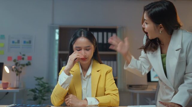 Angry Asian boss reprimanding a young female employee for a work mistake. Upset businesswoman crying and feeling stressed in the office