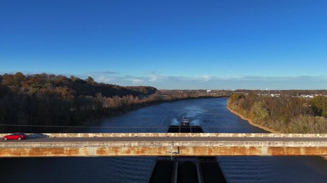 Aerial flyaway shot revealing a bridge, a barge, and trees on the Cumberland River