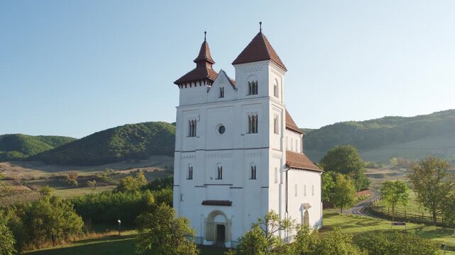 Aerial photo of the historic white church of Herina, Bistrita Nasaud in rural landscape under sunny blue sky