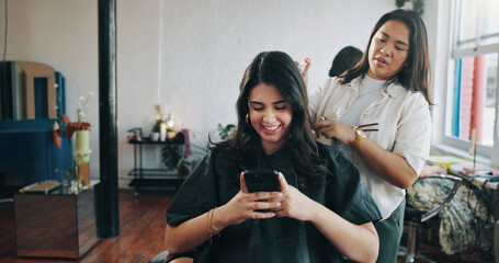 Happy woman, hairdresser and client with phone, spray or talk for trim, texting and service at salon. People, smartphone and customer experience with mobile app, social media or hairstyle at shop