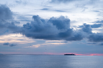Container ship with lights on at sunset