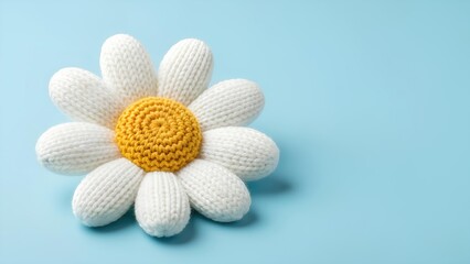 A knitted white wool daisy with an oversized textured yellow center resting on a pastel blue background with clean lighting for soft modern Women’s Day themes