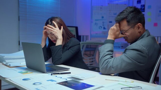 Frustrated Asian business partners having a serious argument and feeling stressed after a project failure while working overtime in the office
