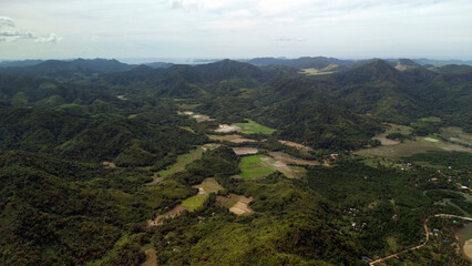 Fototapeta premium Wide aerial drone shot of rolling green hills and mountain ranges with rural agricultural fields in the valley of Barangay Cheey Busuanga Island Philippines