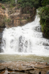 A stunning waterfall cascades over rocky cliffs in a lush, green setting.