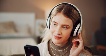 Woman, headphones and phone with music in house, smile and listen with song on web in living room. Person, smartphone and happy for audio on mobile app, streaming subscription or relax at apartment