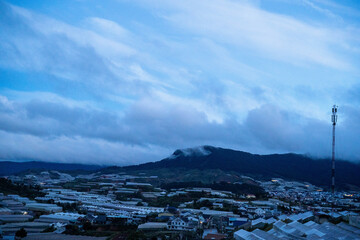 Scenic view of rolling hills and greenhouses at dusk with soft clouds overhead.