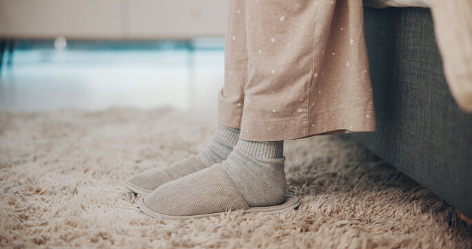 Feet, slippers and wake up in bedroom, morning and floor for comfort, relax and pyjamas in home. Person, legs and shoes with rest for wellness, chill or footwear on carpet for break at apartment