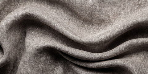 Close up of natural linen fabric with soft folds and textured surface in neutral taupe color