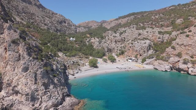 Aerial drone shot reveals Achata Beach in Karpathos, highlighting its clear blue waters, sandy shore, and scenic coastal landscape.