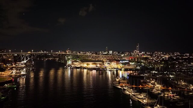Gimbal wide shot panning from Granville Island to downtown Vancouver at night in British Columbia, Canada. 4K