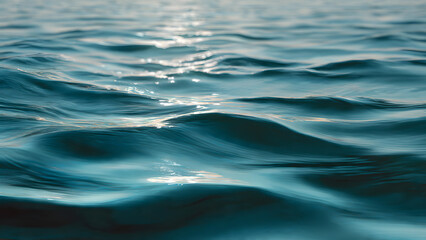 Calm ocean waves with sunlight reflection on surface, serene blue water texture, natural peaceful aquatic scene.