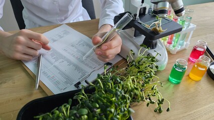 Scientist conducting plant research with microscope and test tubes in a laboratory
