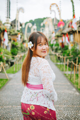 Asian Woman Wearing Traditional Balinese Attire in Penglipuran Village Looking at the Camera