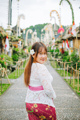 Asian Woman Wearing Traditional Balinese Attire in Penglipuran Village Looking at the Camera
