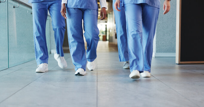 Legs, people and nurses walking in hospital for staff duty, shift change and medical services. Group, employees and team in lobby for patient care, healthcare treatment and ward round for procedure - Powered by Adobe