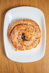 A delicious flaky pastry adorned with sesame seeds rests on a sleek white plate, inviting taste
