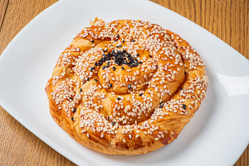 Delicious spiral pastry with a golden crust, adorned with sesame seeds, resting on a plate