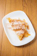 A tempting slice of flaky pastry dusted with powdered sugar and cinnamon on a wooden table