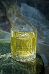 Vibrant green drink sits in a sparkling glass resting on an elegant stone surface