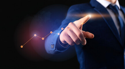 Businessman hand pointing at a futuristic digital interface with a bar chart showing financial growth, stock market success, and business progress.