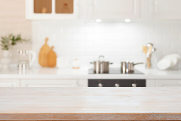 Empty bleached wooden table top over defocused modern kitchen counter workspace interior background