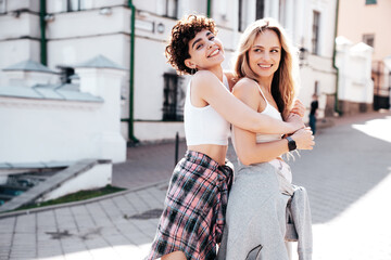 Two young beautiful smiling hipster female in trendy summer white t-shirt and shorts clothes. Sexy...