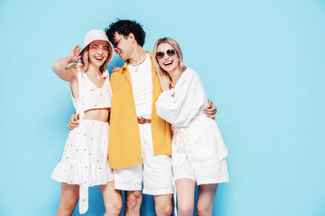 Group of young three stylish friends posing in studio. Fashion man and two cute female dressed in...