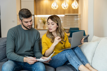 Couple discussing plans while working on laptop at home in a cozy living room during daytime