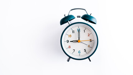 The classic analog clock face clearly shows 9:00, featuring a vibrant multi-colored dial and clean design against a stark white, minimal backdrop.