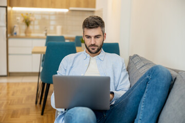 Man working on laptop at home in modern living room during daytime