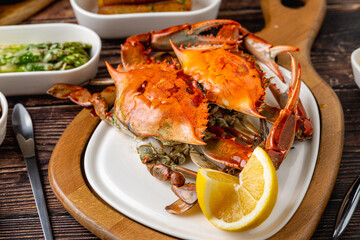 Whole cooked crab plated with lemon and side condiments