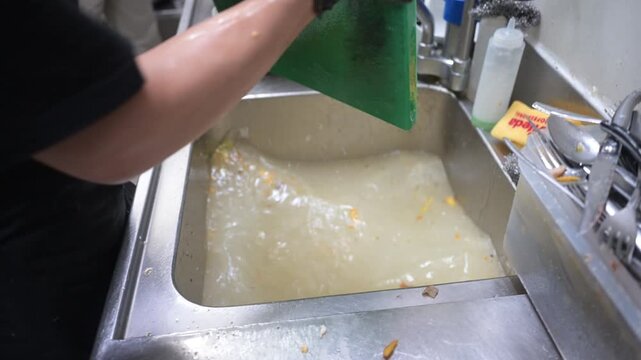 Dishwasher washing a cutting board in a restaurant sink