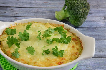 Baked broccoli with cheese on baking dish garnish with parsley