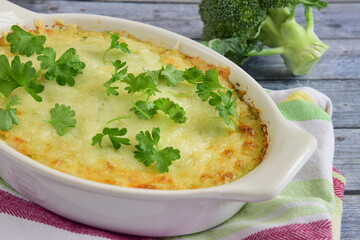Baked broccoli with cheese on baking dish garnish with parsley